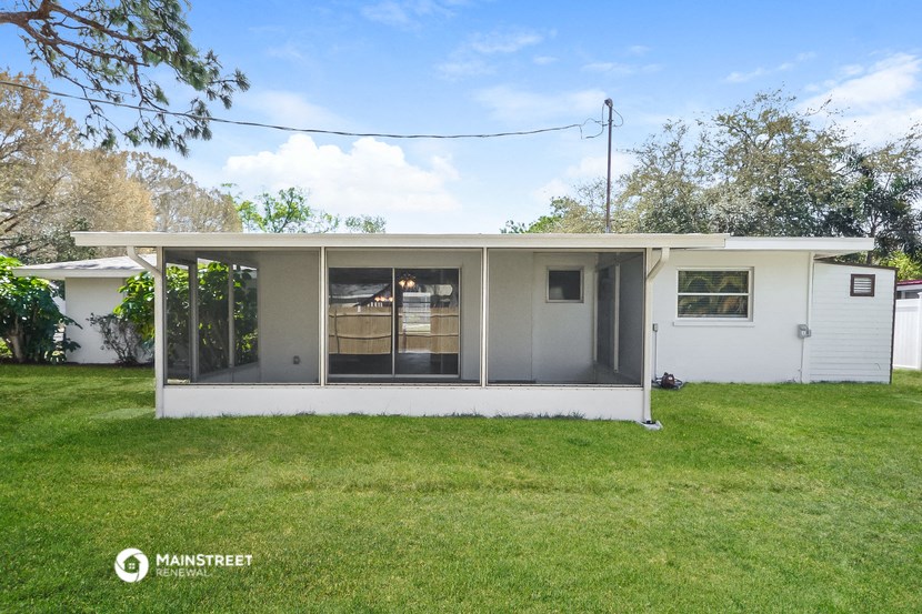a small white house with a covered porch and a lawn