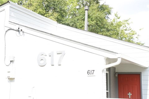 the front of a white house with a red door