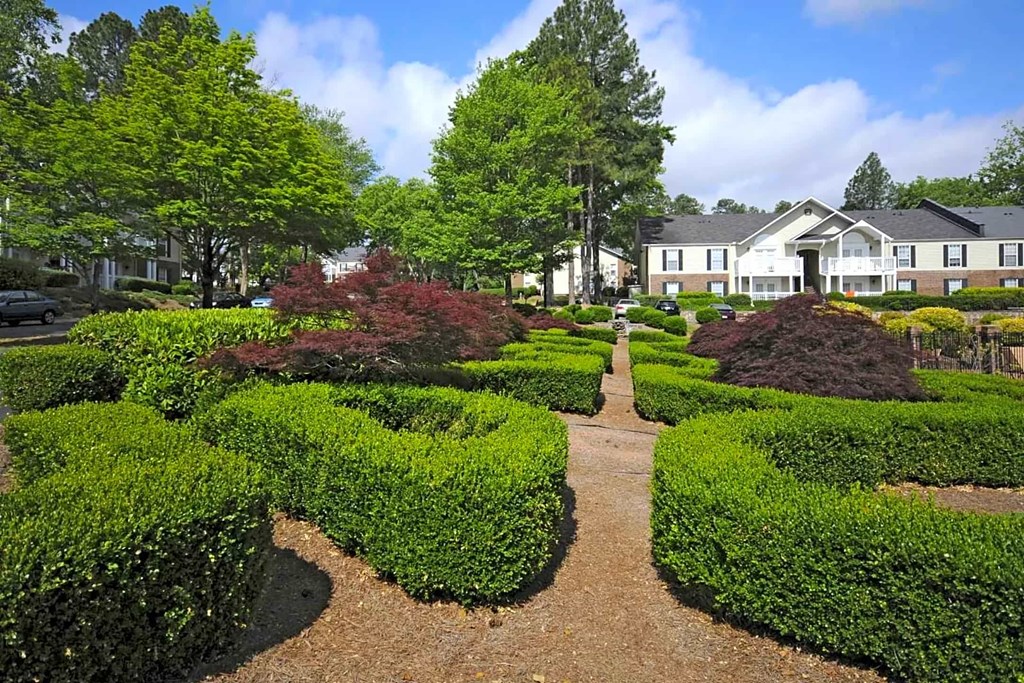 A garden with a pathway and a building in the background.