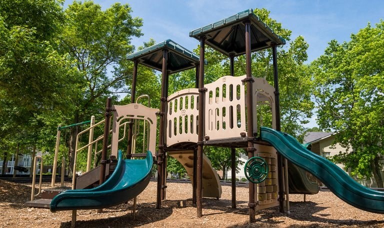 A playground with a green slide and a brown structure.