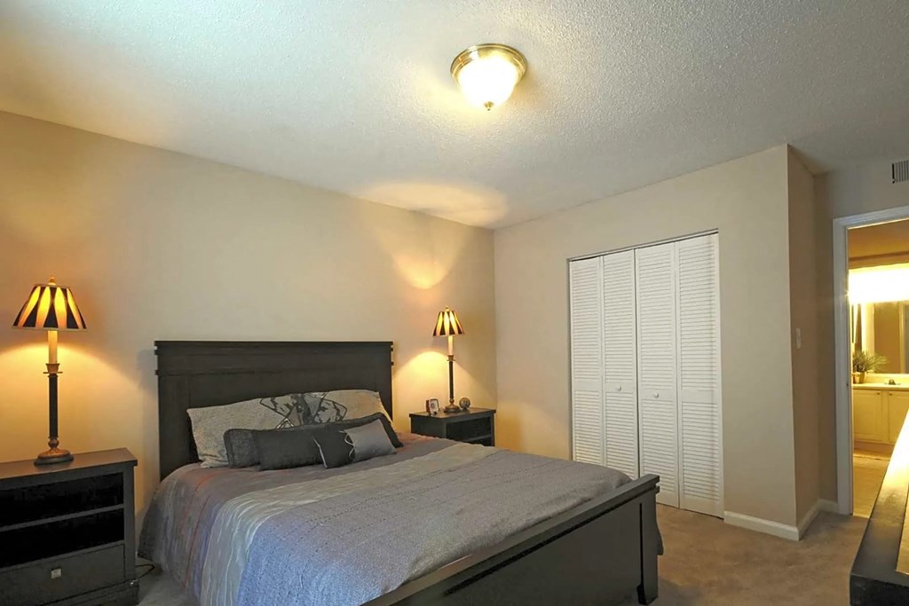 A bedroom with a bed, nightstands, and lamps.