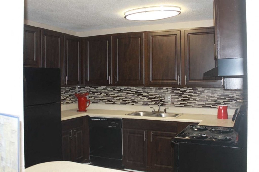 A kitchen with black appliances and brown cabinets.