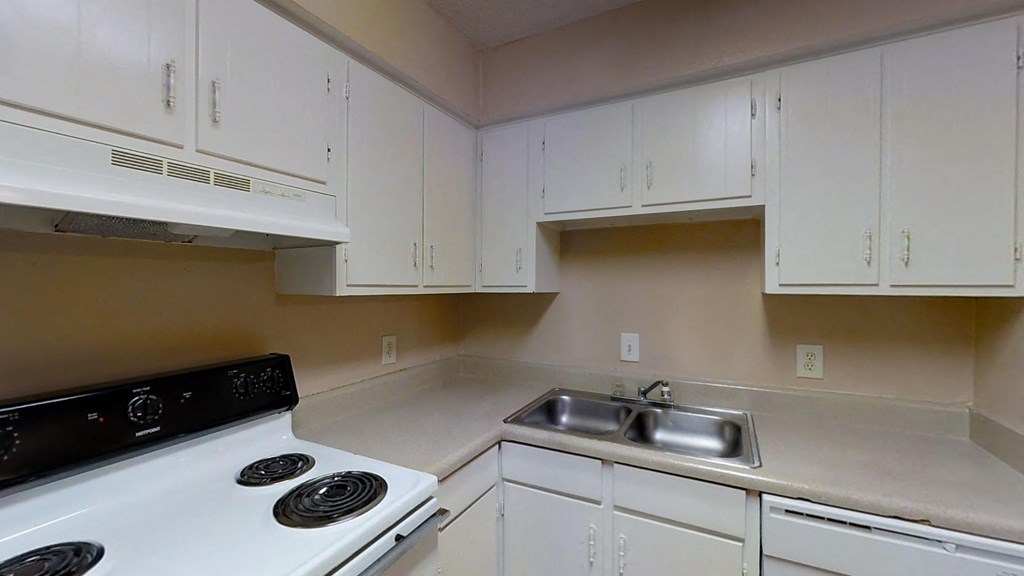 A kitchen with white cabinets and a white stove.