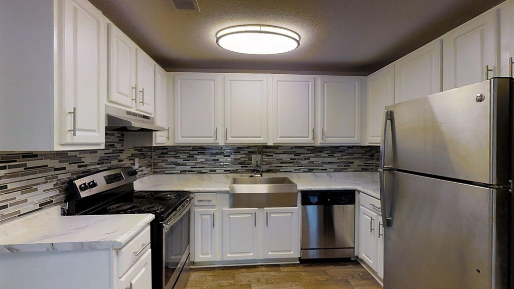 A kitchen with white cabinets and a stainless steel refrigerator.