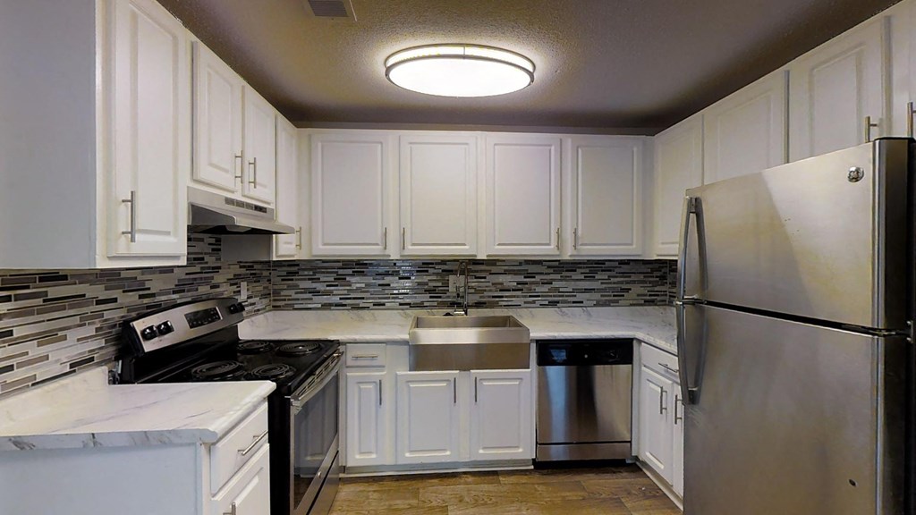 A kitchen with white cabinets and a stainless steel refrigerator.