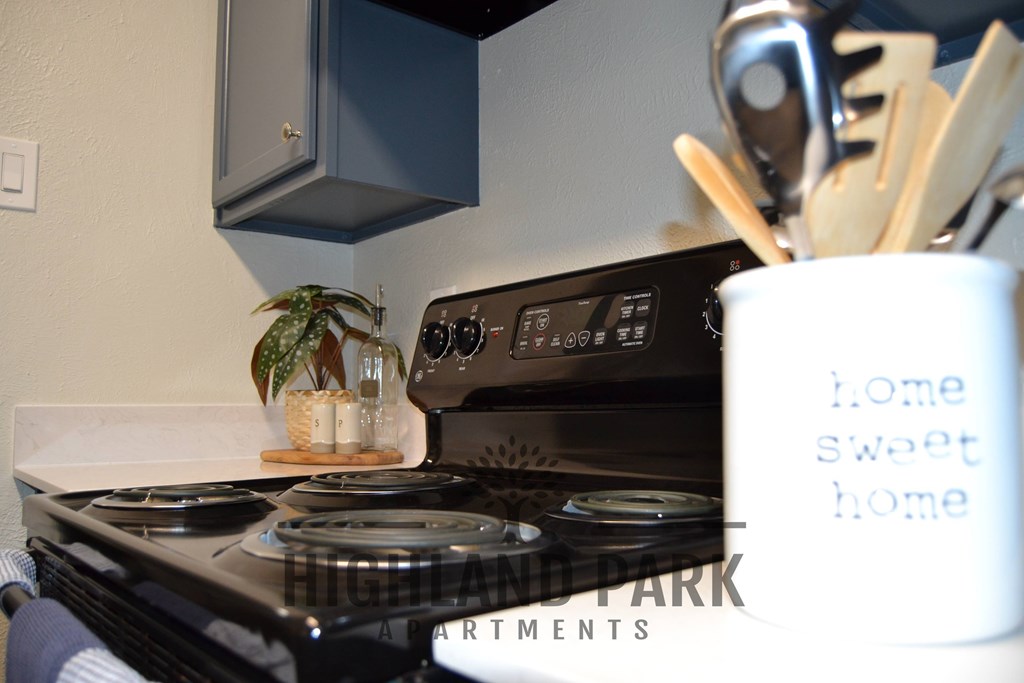 a small kitchen with a stove and a cup of utensils