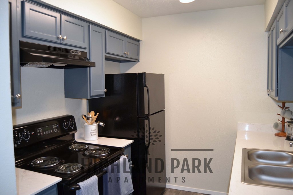 a kitchen with blue cabinets and a black stove and refrigerator