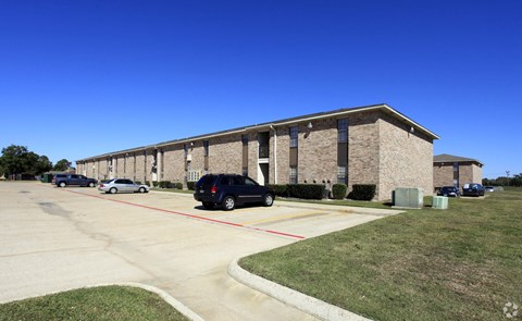 a long brick building with cars parked in front of it