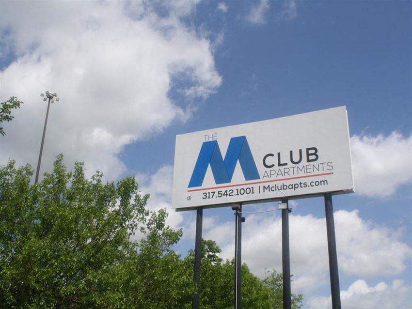 a sign for the club apartments on the side of the road