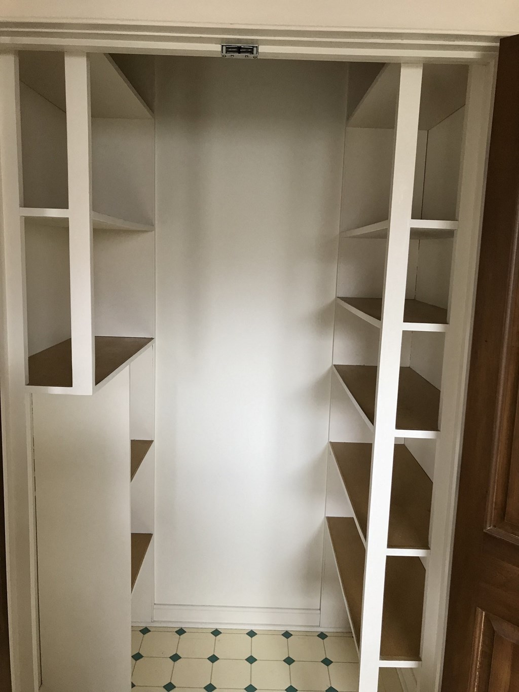 a walk in closet with empty shelves and a door