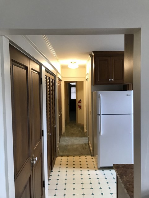 a look down the hallway of a kitchen with a refrigerator and cabinets