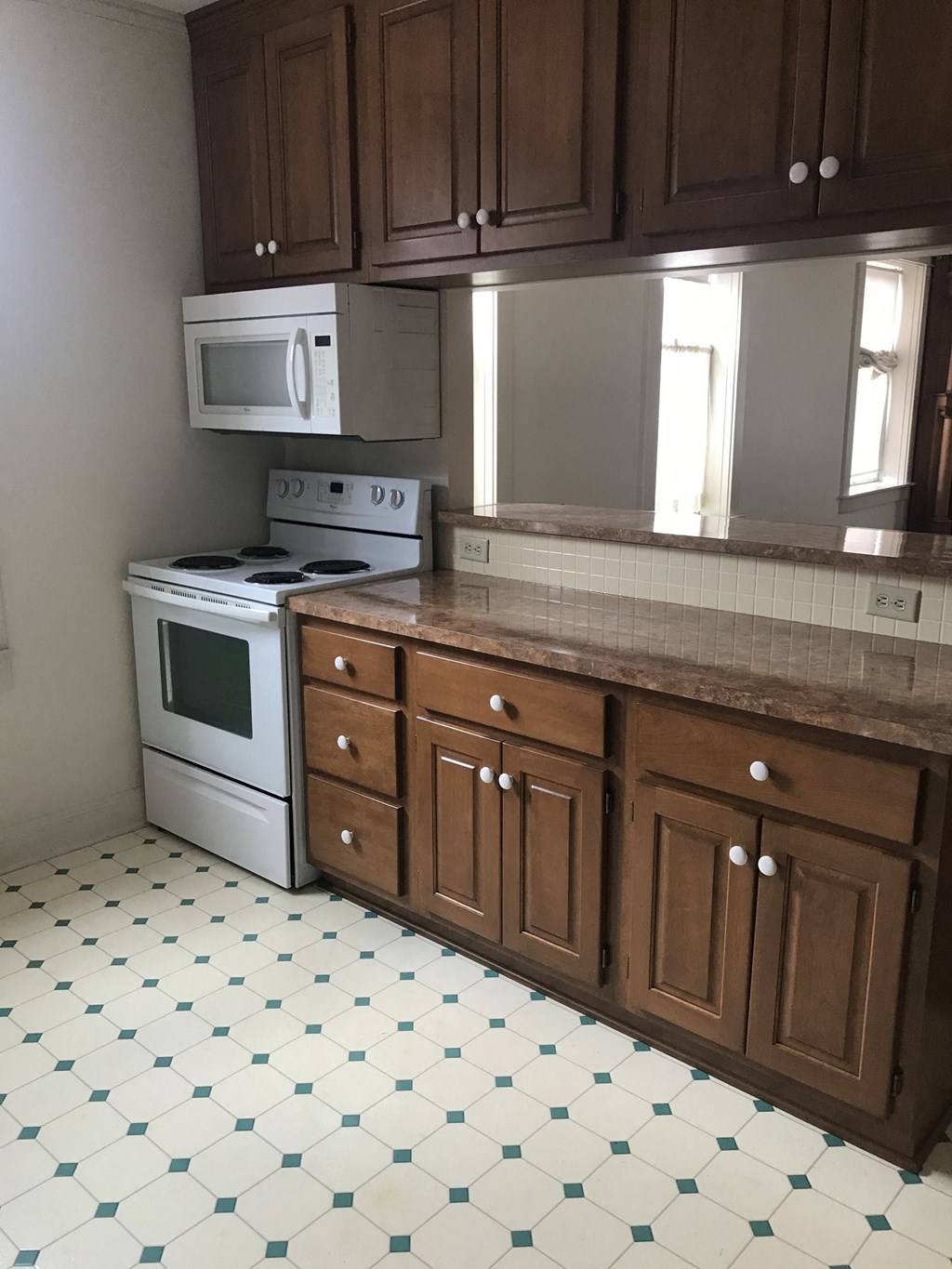 an empty kitchen with white appliances and wooden cabinets