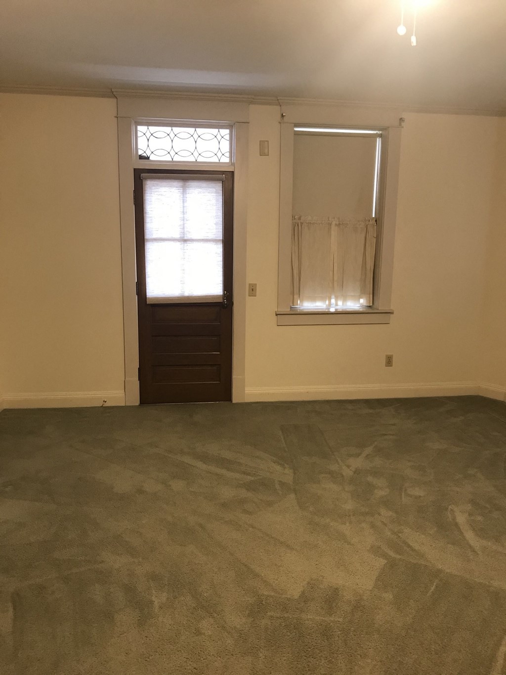 an empty living room with a window and a door