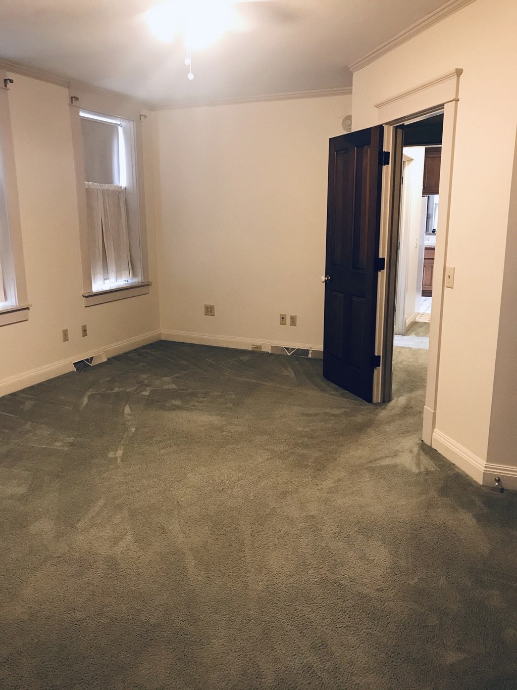a living room with a carpeted floor and a door to a bedroom