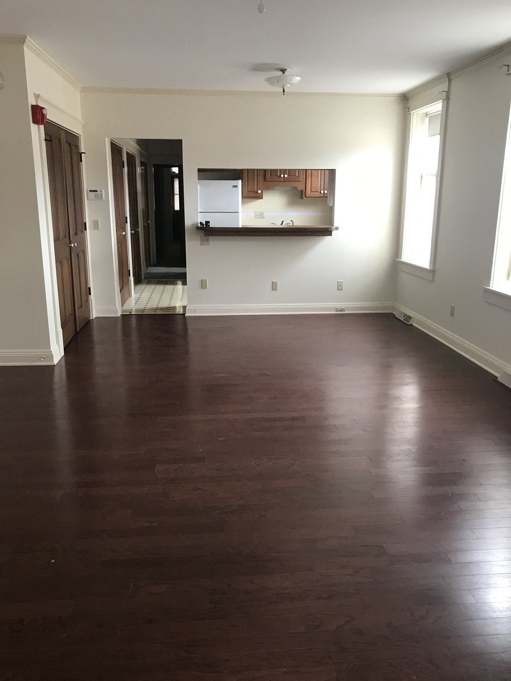 an empty living room with wood floors and a kitchen
