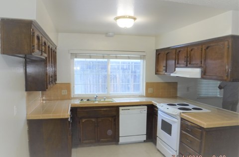 an empty kitchen with wooden cabinets and white appliances