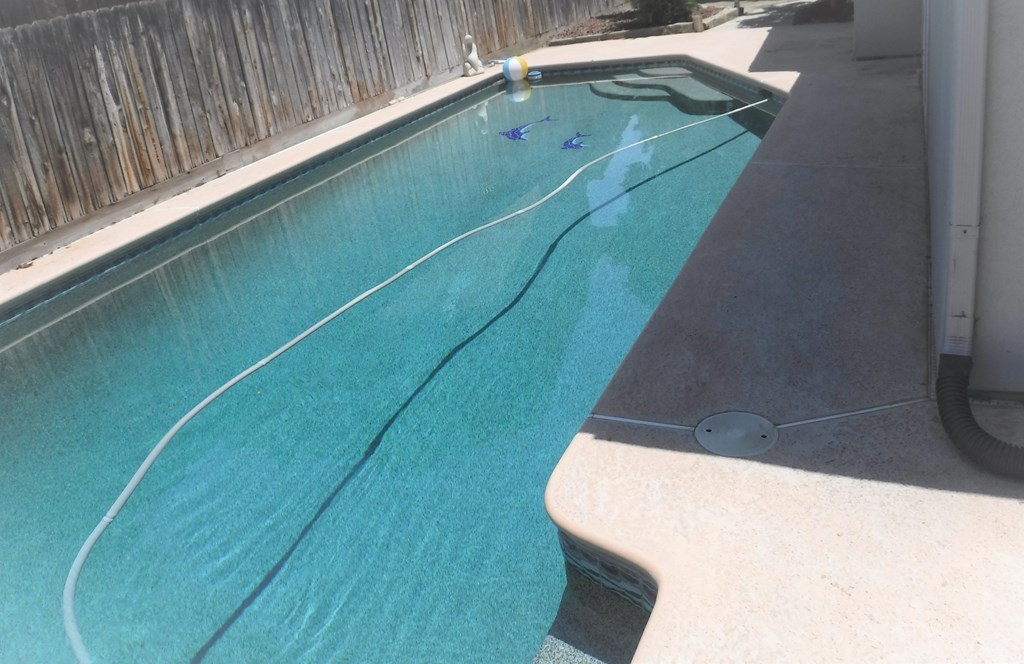 a swimming pool with blue water in the backyard of a house