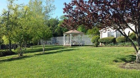 a gazebo in the middle of a yard with a house and trees