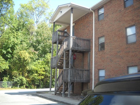 a building with a balcony and a car parked next to it