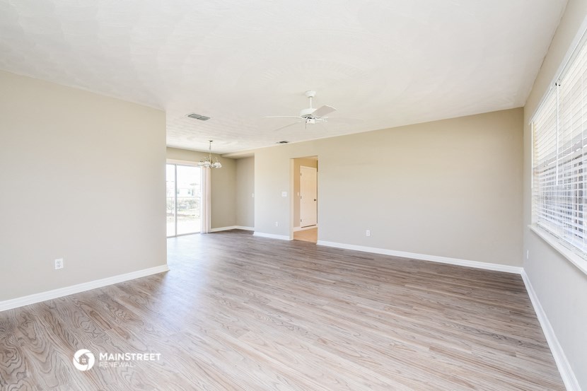 an empty living room with wood flooring and a ceiling fan