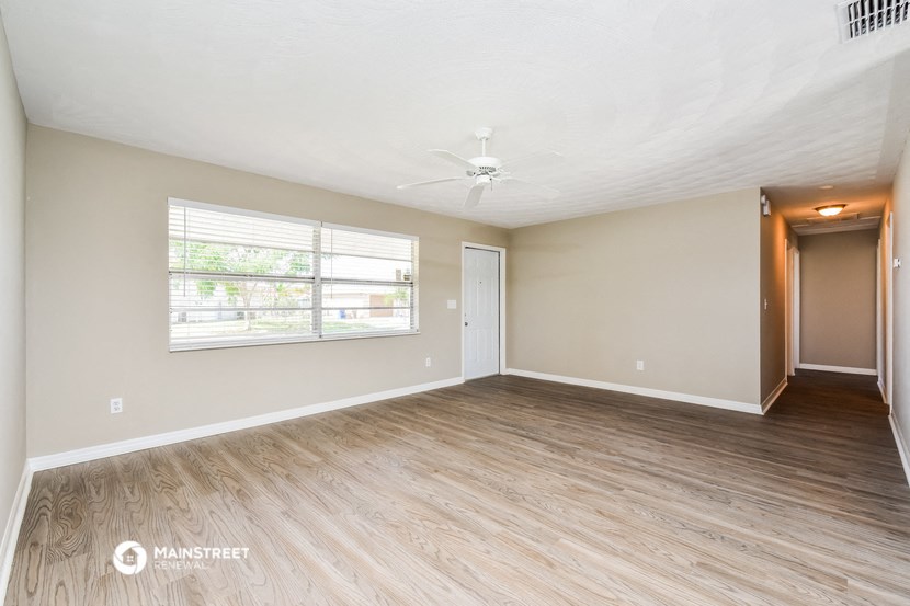 an empty living room with a large window and wood flooring