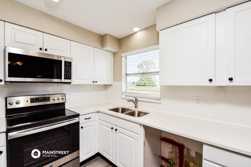 a kitchen with white cabinets and a stove and a microwave