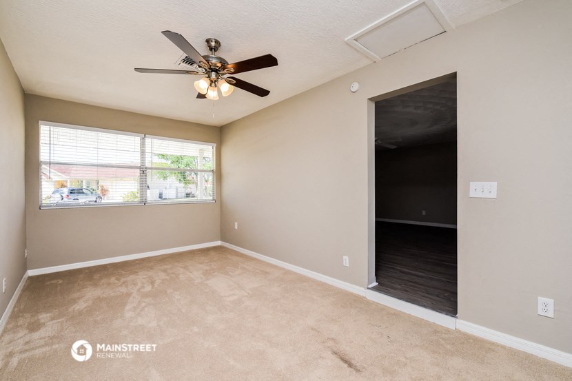an empty living room with a ceiling fan and a window