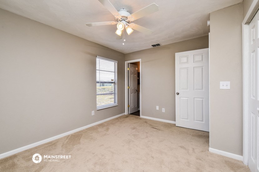 an empty living room with a ceiling fan and a door