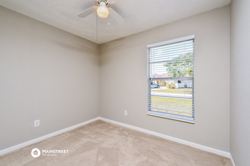 an empty bedroom with a window and a ceiling fan
