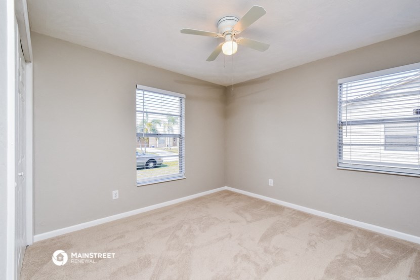 an empty bedroom with a ceiling fan and a window