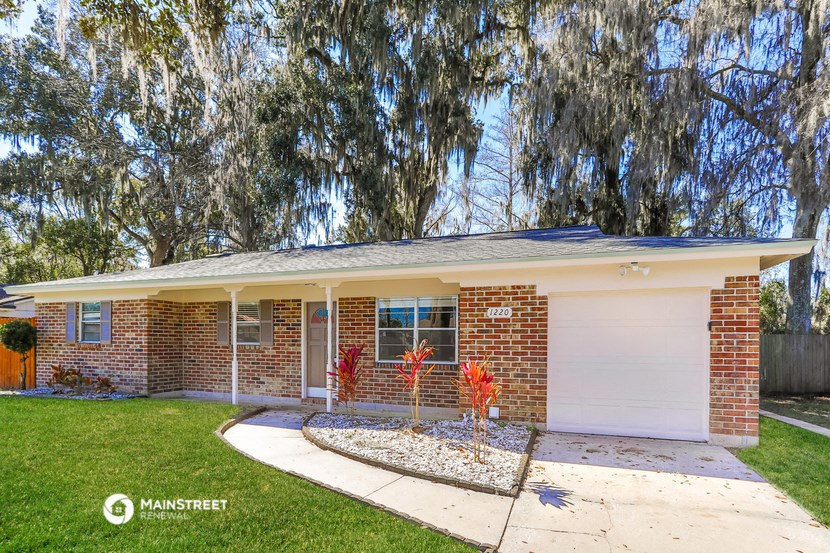 a brick house with a white garage door and a tree