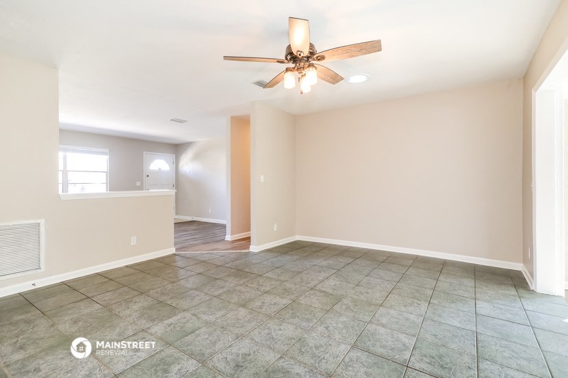 the spacious living room with ceiling fan and tile flooring