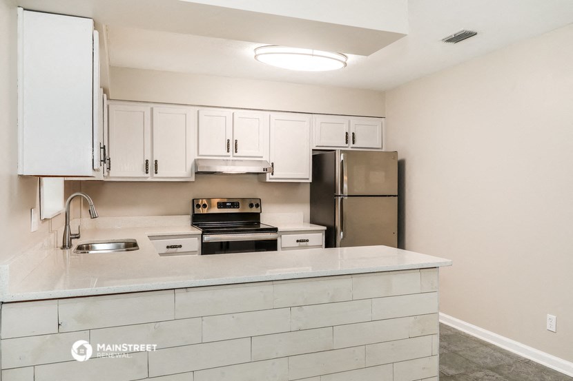 an empty kitchen with white cabinets and a stainless steel refrigerator