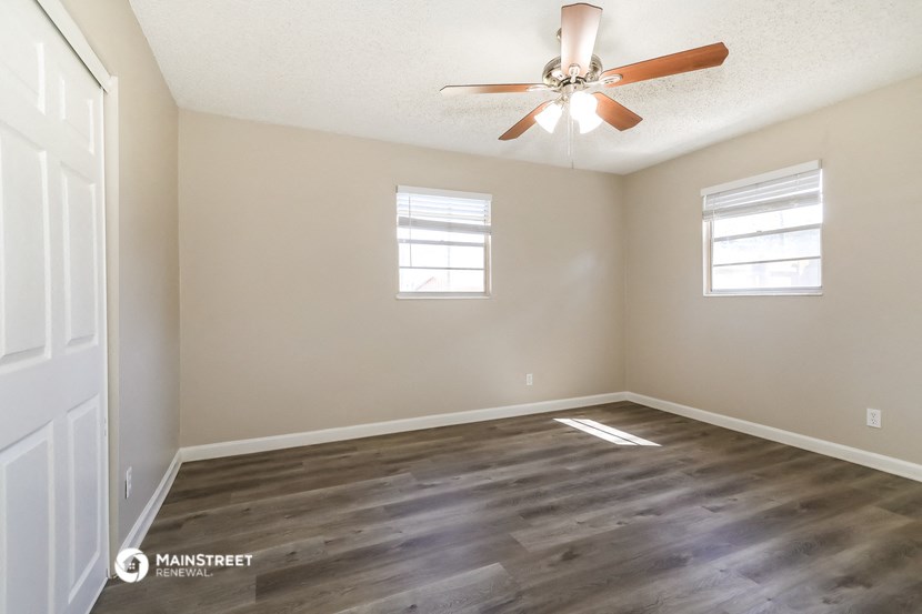 the spacious living room with hardwood floors and a ceiling fan