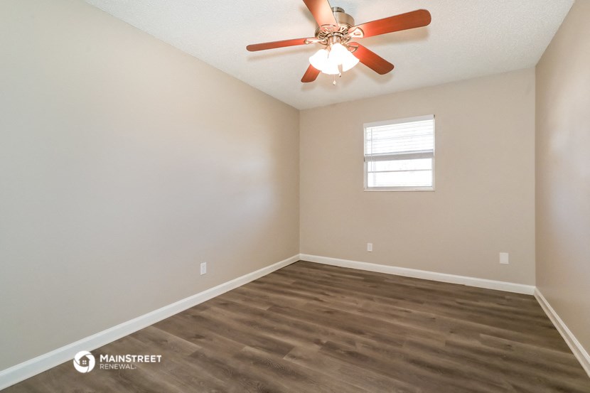 the spacious living room with ceiling fan and wood flooring