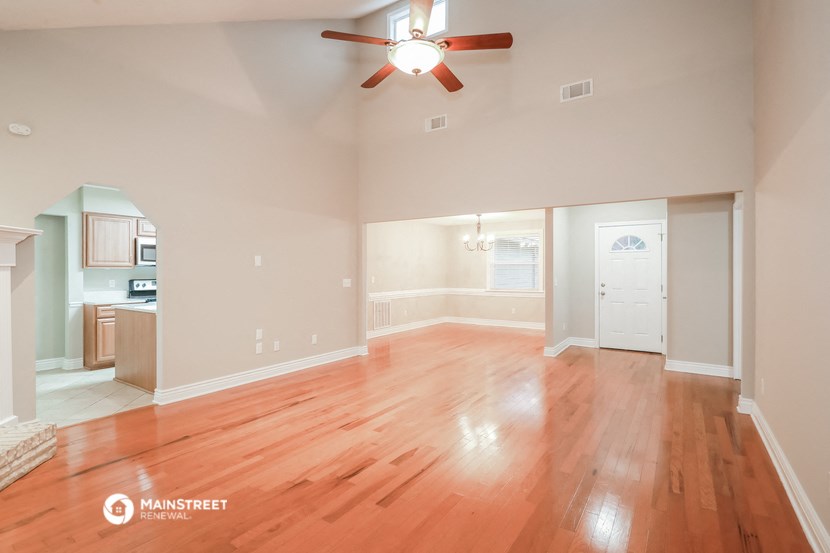 an empty living room with wood floors and a ceiling fan