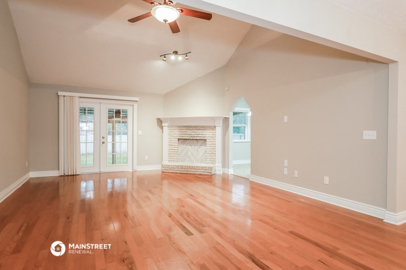 the living room with wood floors and a fireplace