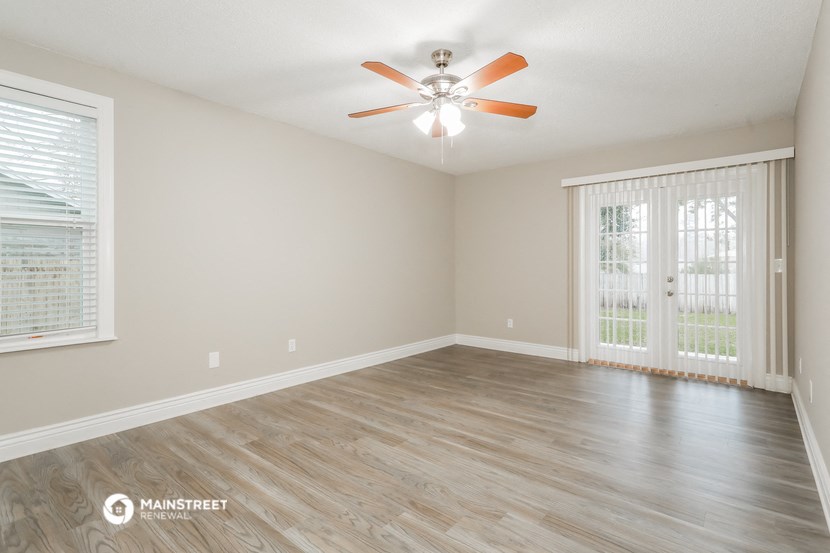 an empty living room with a ceiling fan and a window