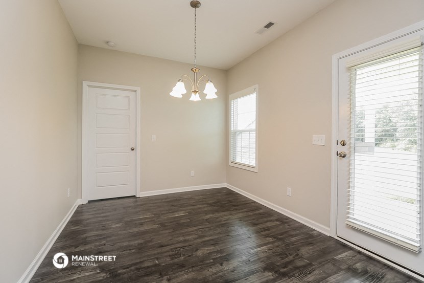 the spacious living room with wood flooring and a white door