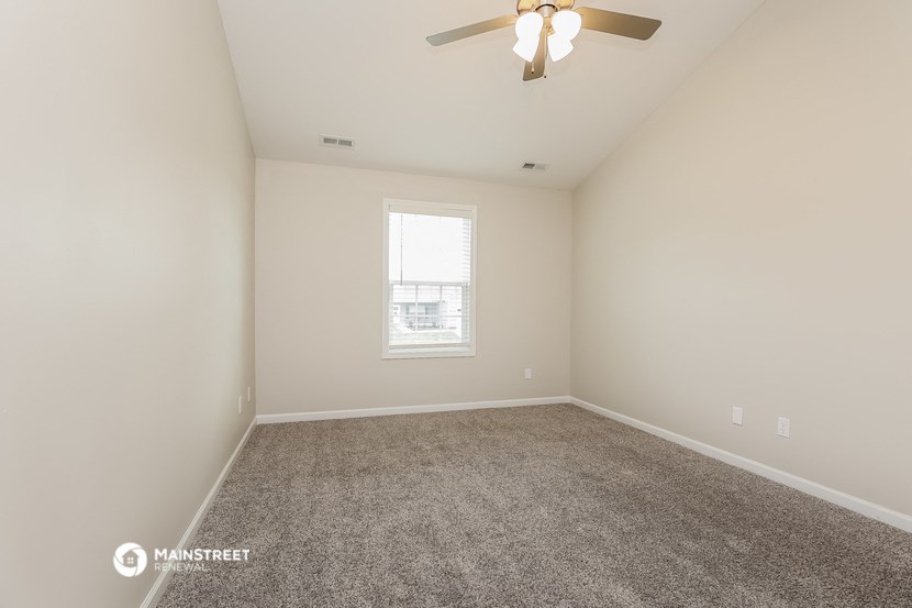 an empty room with a ceiling fan and a window