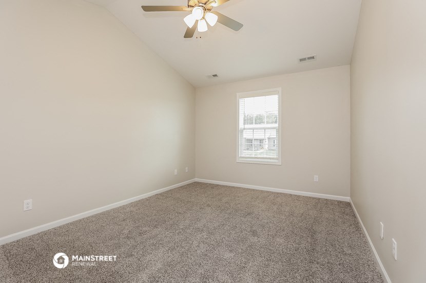the spacious living room with carpeting and a ceiling fan