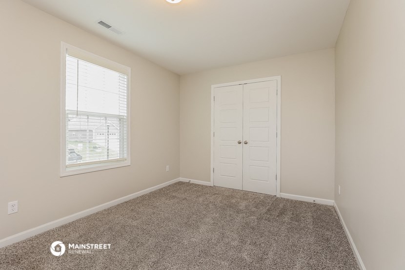 a bedroom with carpet and a door and a window