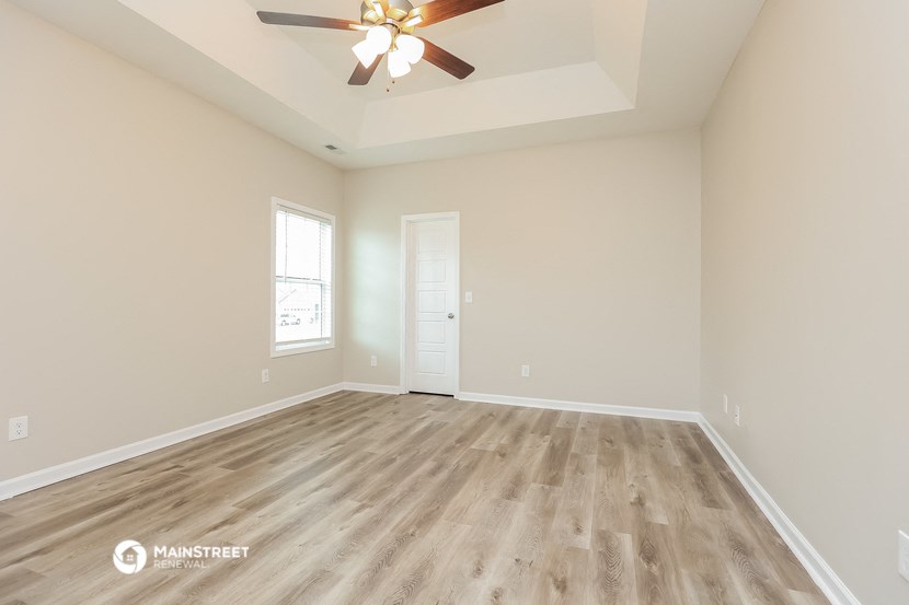 the spacious living room with hardwood floors and a ceiling fan