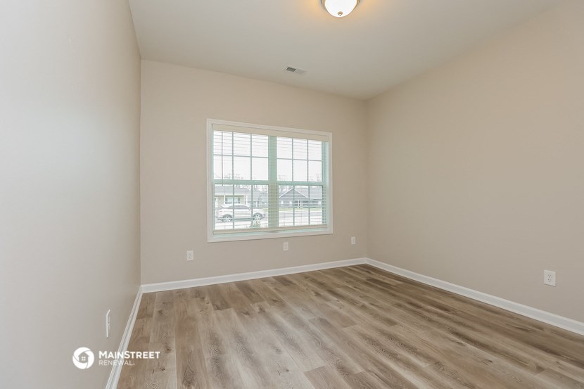 the spacious living room with hardwood flooring and a window