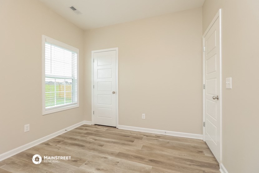 the living room of a home with a wooden floor and white doors