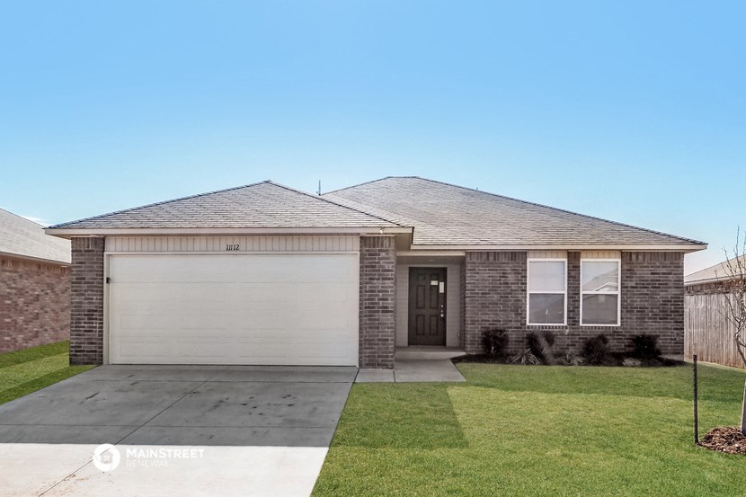 a brick house with a garage door and a lawn