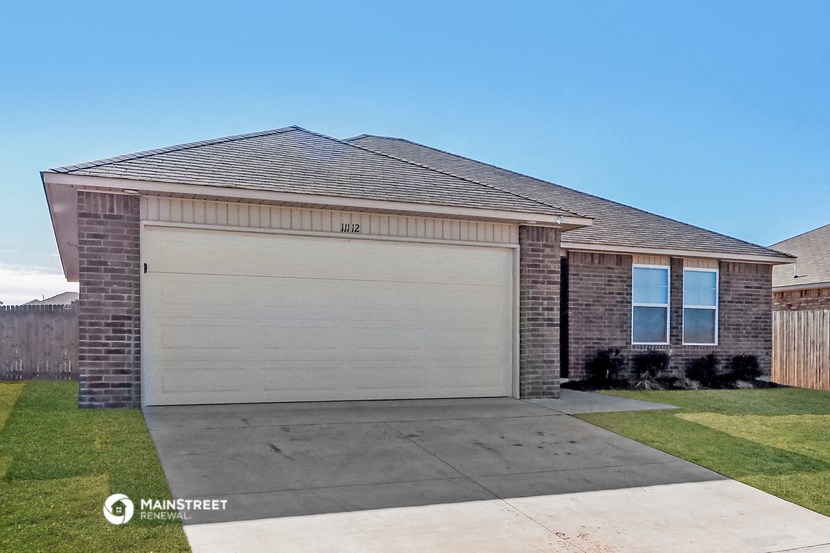 a brick house with a garage door and a lawn