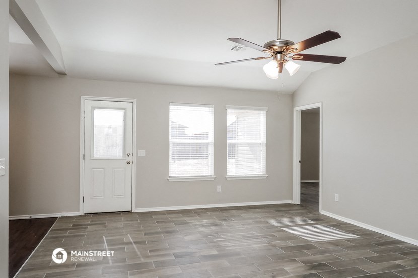 the living room of an empty home with a ceiling fan