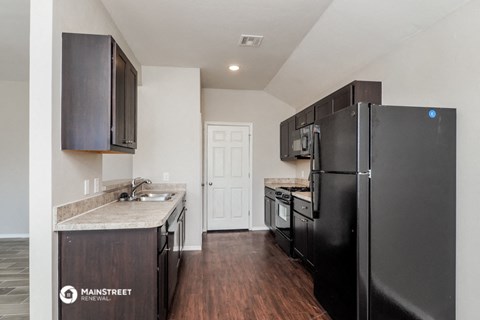 the kitchen of a home with black appliances and a refrigerator
