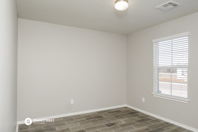 the living room of an apartment with a tile floor and a window